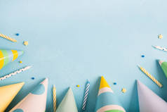 生日宴会的背景。狂欢节的帽子，意大利面和蜡烛在淡蓝色的表面。顶视图、平铺、复制空间