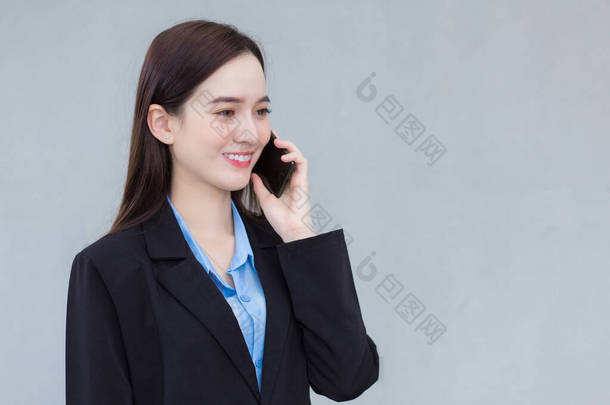 亚洲职业女性在重要业务中使用智能手机时穿着黑色西服.