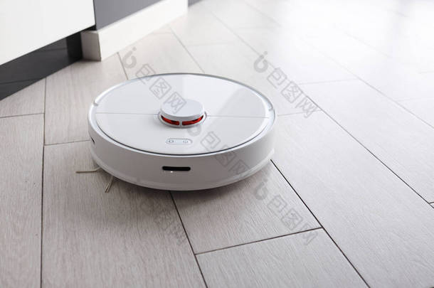 Robot vacuum cleaner removes dust in room on floor. Vacuum cleaner in ordinary apartment. modern hou