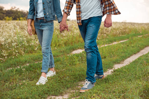 在野外散步时牵手的一对夫妇被裁剪的照片