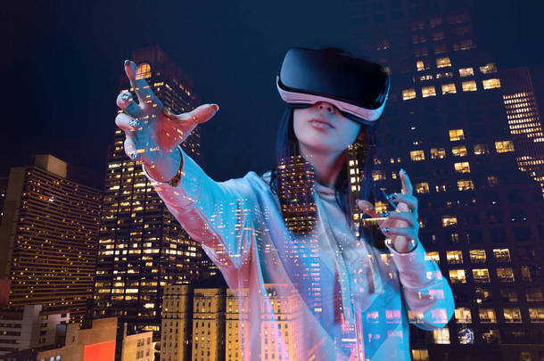 双曝光黑发女孩手势，而穿着虚拟现实耳机和现代城市与摩天大楼在夜间