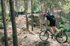 在森林中骑山地自行车保护头盔的男性极端骑自行车的侧面观察