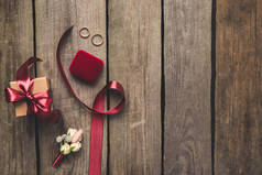平躺与丝带, 结婚戒指, 胸花和礼物在木桌上