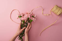 裁剪拍摄的妇女拿着粉红色康乃馨花孤立在粉红色