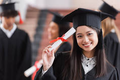 亚洲毕业生，头戴帽子，面带微笑，并持有文凭