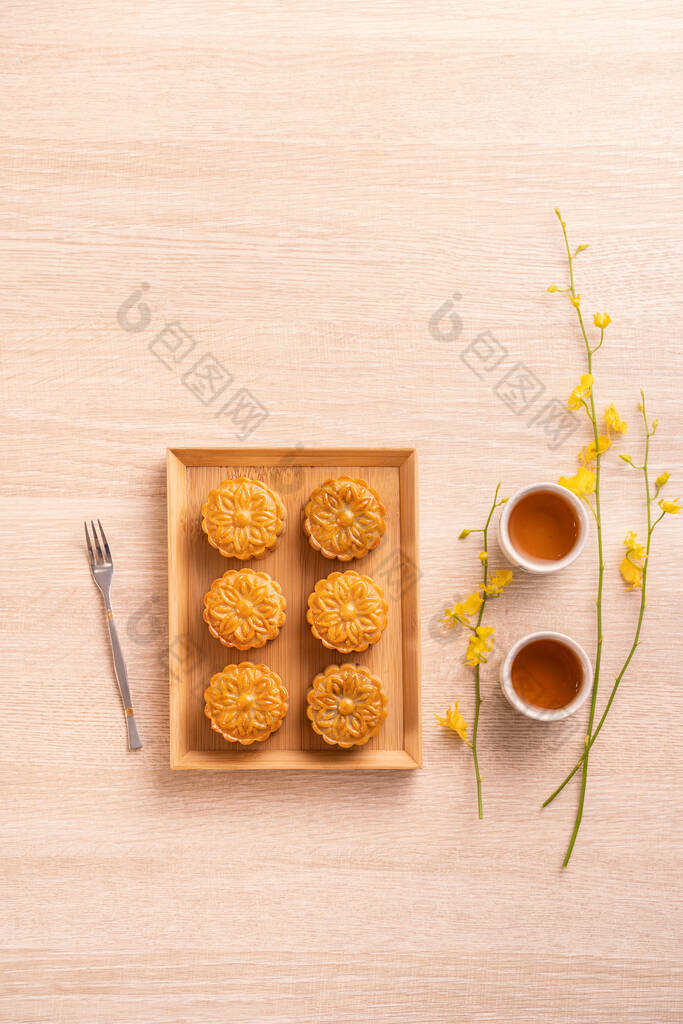 中秋节月饼、月饼、茶具在明亮的木制桌子上，有复制空间、顶视图、平铺、头顶拍摄等概念设计