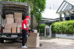 身穿红色制服的亚洲送货男子将包裹箱送到家中的妇女收件处
