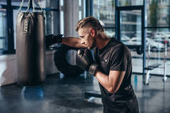 在健身房里用打气筒训练帅气的肌肉拳击手的侧视图
