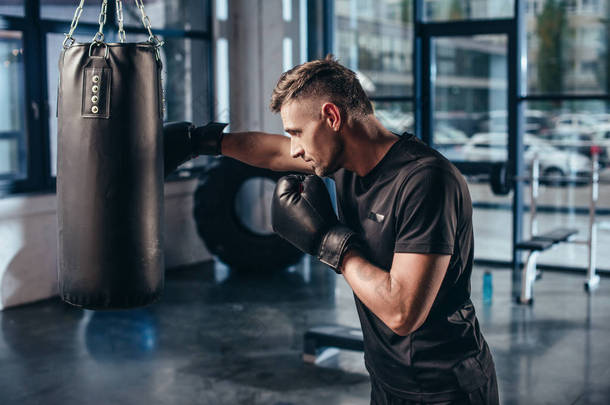 在健身房里用<strong>打气筒</strong>训练帅气的肌肉拳击手的侧视图