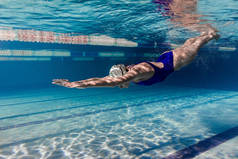 游泳衣中女游泳运动员的水下图片及泳池的护目镜训练