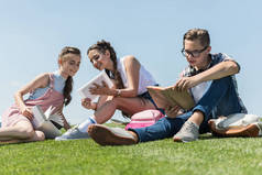 在公园里用书和数码片学习微笑的青少年的低角度观