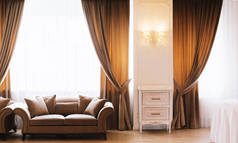 酒店房间或餐厅的照片, 有优雅的窗帘, 沙发, 大窗户, 墙上有老式的灯