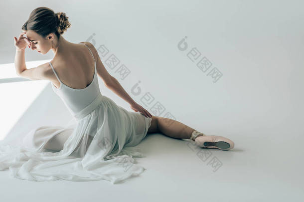 优雅的芭蕾舞女演员坐在<strong>白色</strong>的礼服和芭蕾<strong>舞鞋</strong>后视图