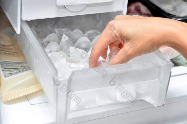 一个女人从冰柜里拿出冰块来冷却饮料