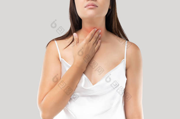 在灰色背景下,亚洲妇女喉头或甲状腺<strong>疼痛</strong>.酸倒流或心脏灼伤，<strong>颈部疼痛</strong>，人体问题概念