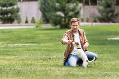 年轻人在草坪上与杰克 · 罗斯塞尔犬玩耍的选择性焦点