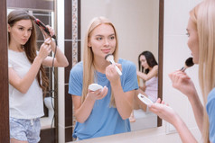 美丽的女孩化妆刷粉底粉在浴室