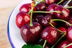 樱桃在一个木桌上的白色搪瓷碗, 新鲜的樱桃, 季节性浆果, 樱桃, 成熟的浆果