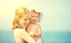 幸福的家庭，在海滩上。母亲和婴儿的女儿