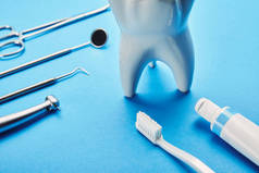 在蓝色背景下, 可近距离查看白色牙齿模型、牙刷、牙膏和不锈钢牙科器械