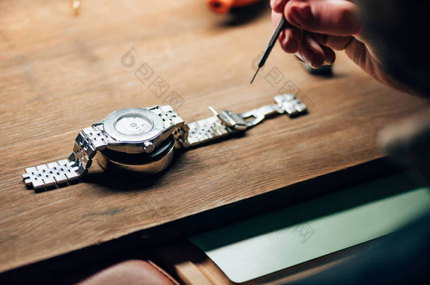 带螺丝刀和腕表的钟表匠站在桌子上的剪影