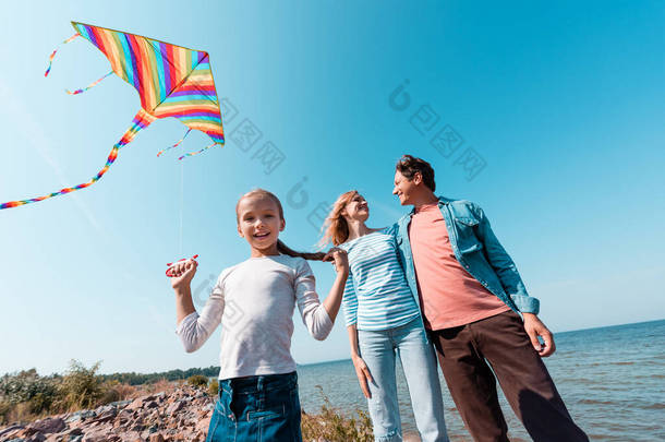 <strong>家长</strong>在周末抱着孩子在沙滩上放风筝时的低视角