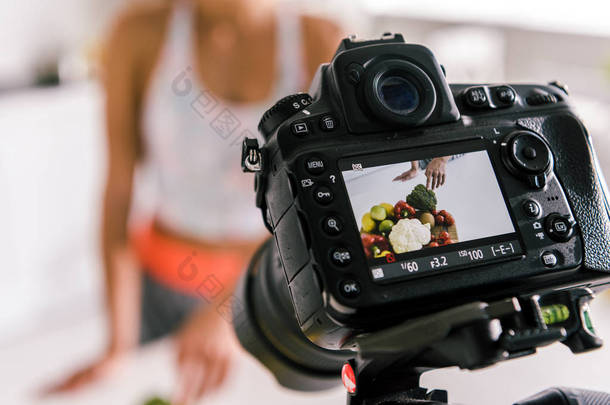 选择性聚焦数码相机与女运动员手势附近的蔬菜在屏幕上