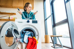 年轻女子倚在破碎的洗衣机