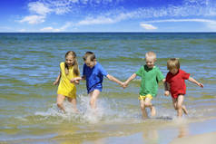 两个女孩和两个男孩穿着五颜六色的 t恤在沙地上奔跑