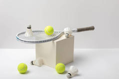 网球拍和亮黄色的网球与穿梭球在立方体上的白色背景
