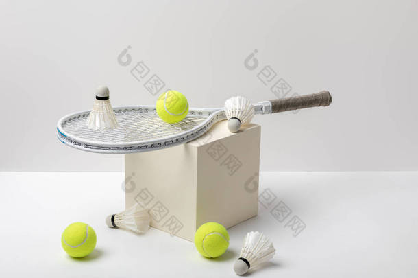 网球拍和亮黄色的网球与穿梭球在立方体上的白色背景