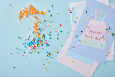 蓝色背景的生日贺卡附近彩色艳丽的五彩纸屑的顶视图