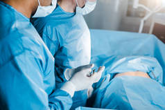 裁剪视图护士在制服和医疗口罩给外科医生医疗设备