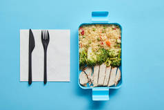 午餐盒的顶视图，蓝色背景有里索托、西兰花和鸡肉