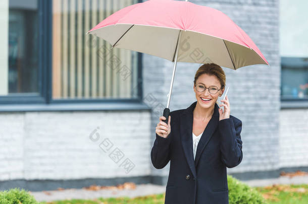 带雨伞和智能手机的成熟女性