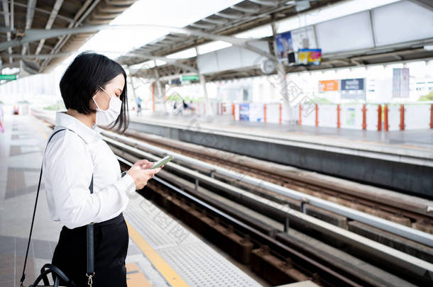 亚洲女人在等地铁时使用智能手机的特写照片.