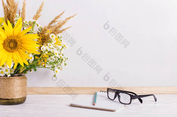 白板上的花瓶里放着书、眼镜、记号和一束鲜花。教师节和9月1日的概念。复制空间.