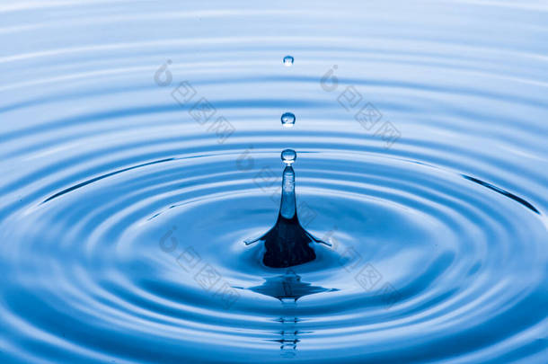 water drop splash in a glass blue colored shot of water that is dripping and reflecting water.soft f