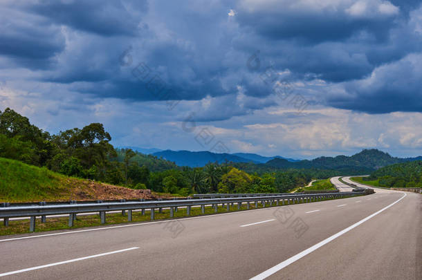 通往<strong>马来西亚</strong>卡梅隆高地的空高速公路或高速公路。在蓝色阴霾中，多云的天空和郁郁葱葱的<strong>热带</strong>雨林中丘陵地形的壮观景色.