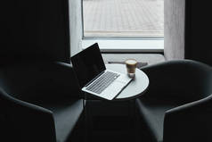 咖啡桌上有空白屏幕和咖啡杯的笔记本电脑