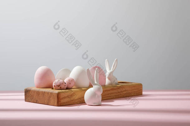 木制木板上的复活节彩蛋，用<strong>粉色</strong>和灰色<strong>装饰</strong>兔子