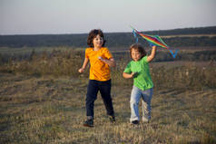 孩子们在夏日日落草地上放风筝