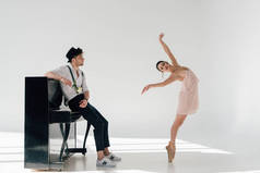 英俊的音乐家拿着玫瑰, 看着跳舞美丽的芭蕾舞演员