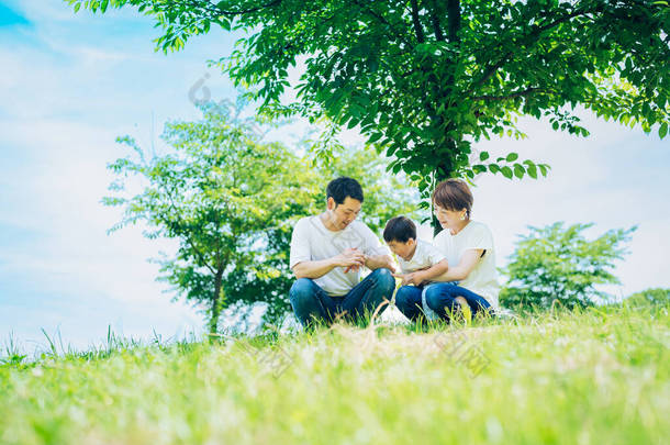 Parents and their child sitting on a sunny green space on fine day