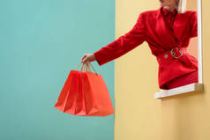 穿红色购物袋的时尚女子在装饰橱窗上拍
