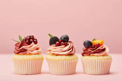 甜纸杯蛋糕与水果和浆果在粉红色的表面