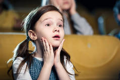 在电影院看电影的可爱的担心的孩子的选择性焦点