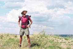 旅行者与背包和旅游垫站立在夏天草甸