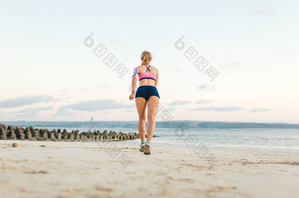 运动员与智能手机后视图在沙滩上运行臂章案例慢跑