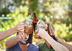 为夏天干杯在夏日的阳光下，一群年轻的朋友一边在外面喝着几杯酒一边敬酒。.